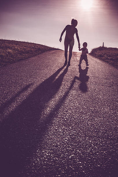 istock Baby walking with help of its parents - first steps 614412480