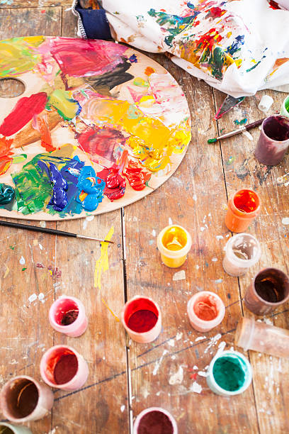 istock Painter's tools on table-oil paints cans, palette and durty pattern 614414566