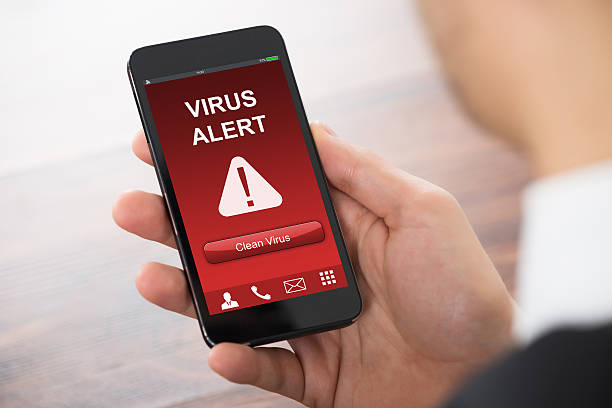 istock Businessman Holding Mobile Phone With Virus Alert 614415116