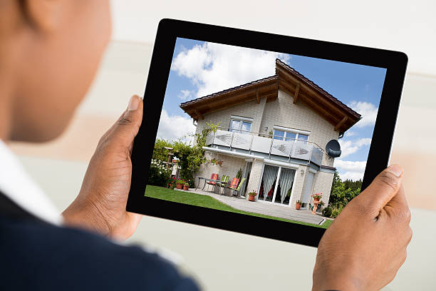 istock Person Looking At House On Digital Tablet 614415572