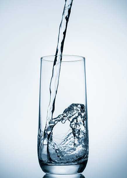 istock water pouring into glass on blue background 614415612