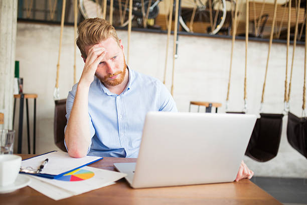 istock Young thoughtful businessman using laptop during coffee break. 614418710
