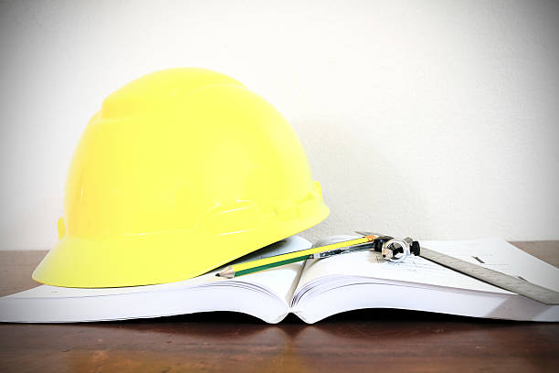 istock hard hat with pencil compasses and rulers/book on table 614418740