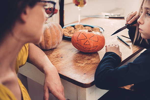 istock Daughter and mother creating Jack-O-Lantern 614419000