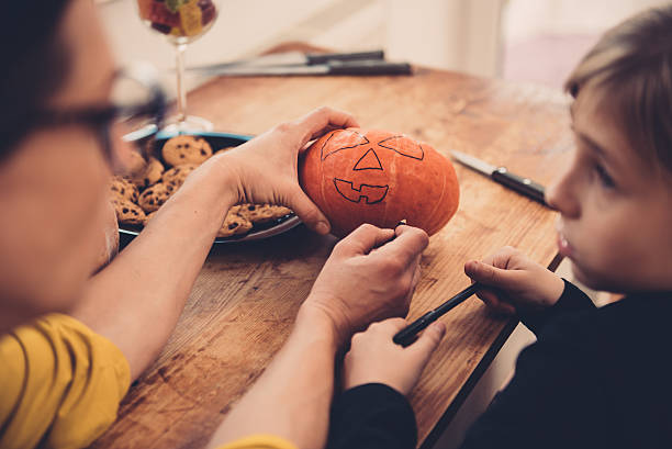 istock Daughter and mother creating Jack-O-Lantern 614419244