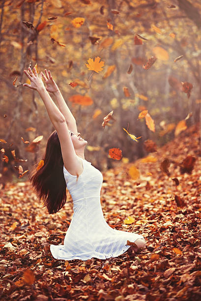 istock Autumn leaves falling on happy young woman in forest 614420214