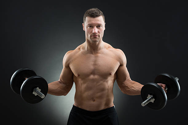 istock Confident Muscular Man Holding Dumbbells 614420754