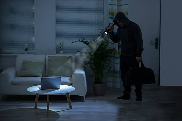 自宅でラップトップの上に懐中電灯を保持する強盗 - burglary burglar thief house ストックフォトと画像