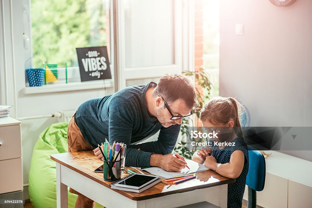 Father helping daughter to finish homework Father helping daughter to finish homework in her room Father Stock Photo