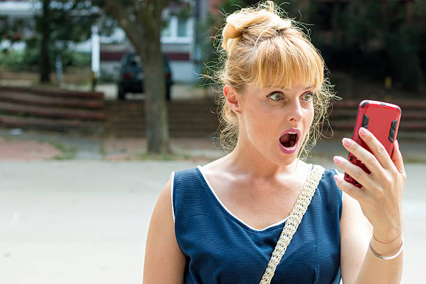 istock Beautiful woman surprised looking at mobile phone 614424982