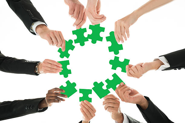 istock Business Team Joining Jigsaw Pieces In Huddle 614430018