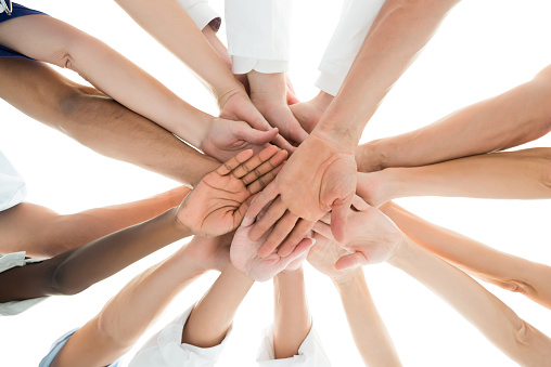 Directly below shot of medical team piling hands against white background