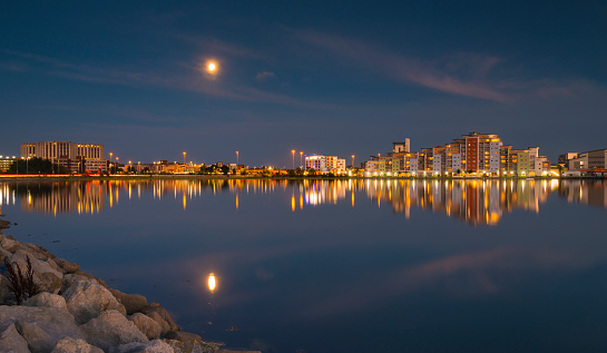Perfect reflections are cast on the still harbour waters with the bright lights of Poole's backwater developments illuminating the view. The moon also reflects in the sea water