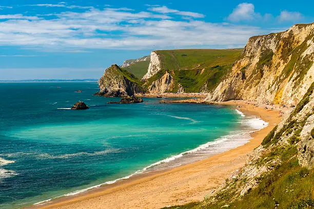 Jurassic coastline with bright blue green sea, deep blue skies and yellow sands and cliffs around the Lulworth, Durdle Door, Worbarrow beaches and coves