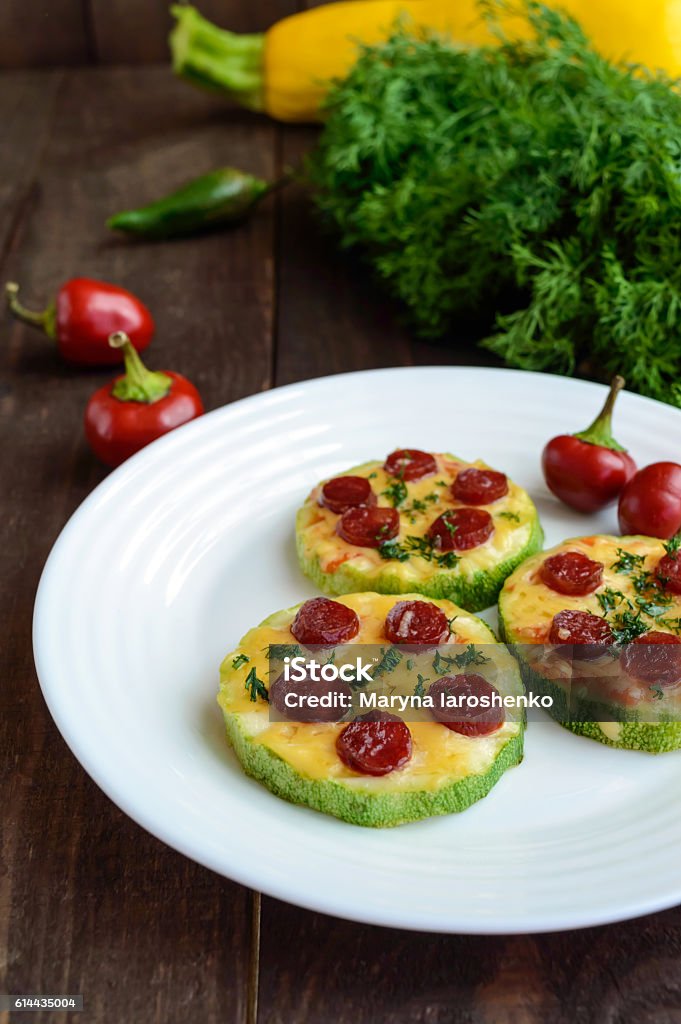 Small zucchini pizza on the circles with pepperoni and mozzarella. Small zucchini pizza on the circles with pepperoni and mozzarella. On a dark wooden background. Backgrounds Stock Photo