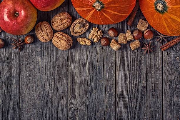 istock Wooden background with pumpkin, apples, nuts and spices. 614435318