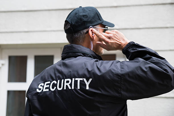 agent de sécurité à l’écoute de l’écouteur contre le bâtiment - bodyguard photos et images de collection