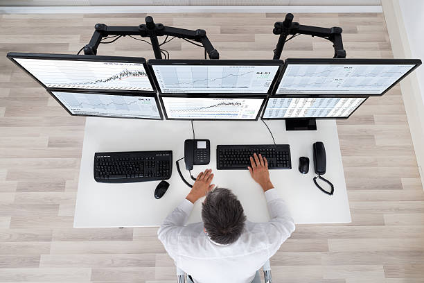 Stock Market Broker Looking At Graphs At Desk