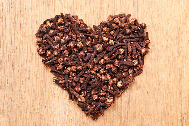 Heart form made from spice cloves on wooden background