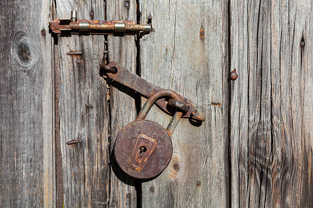 istock Old rusty padlock and latch on a wooden door 614440406