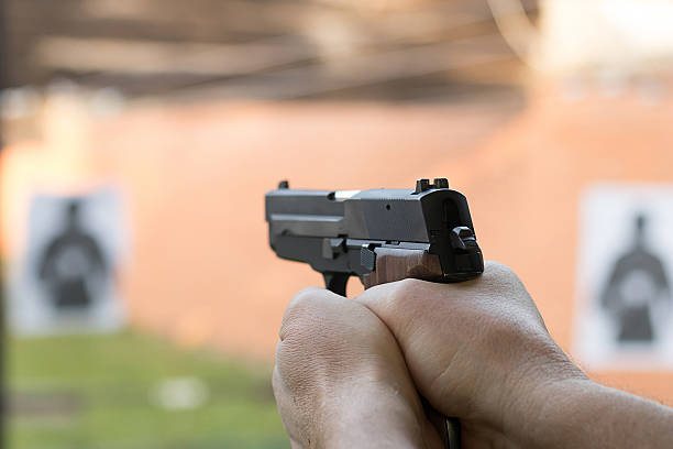 стрельба из пистолета. человек, направленный пистолет в стрельбище. - armed forces human hand rifle bullet стоковые фото и изображения