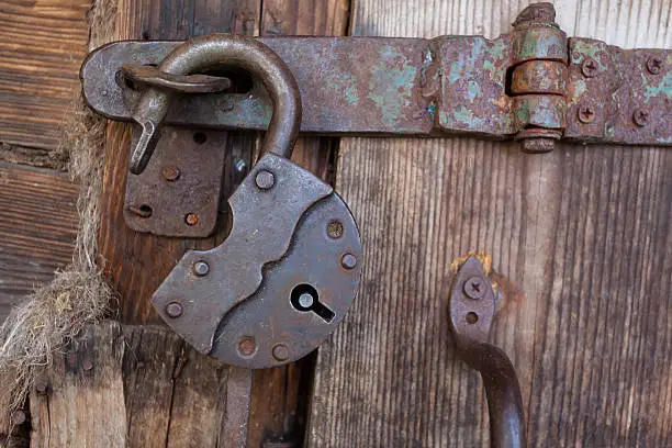 Photo of Old rusty padlock and latch on a wooden door