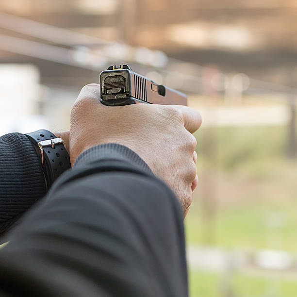 istock Shooting with a pistol. Man aiming pistol in shooting range. 614440712