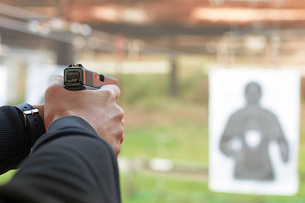istock Shooting with a pistol. Man aiming pistol in shooting range. 614440868