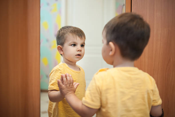 menino olhando para si mesmo perto do espelho; - wondered - fotografias e filmes do acervo