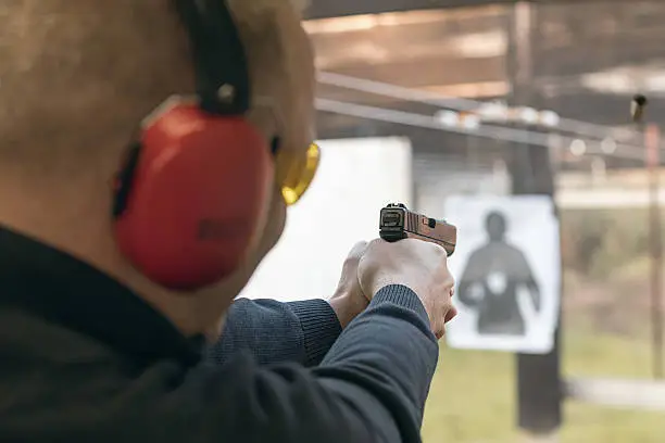 Photo of Shooting with a pistol. Man aiming pistol in shooting range.