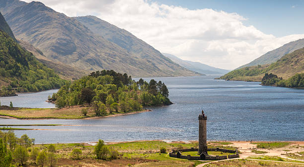 Glenfinnan Monument and Loch Shiel The 1815 tower memorial to the 1745 Jacobite Uprising  stands on the shore of Loch Shiel under the picturesque mountains of the West Highlands of Scotland. glenfinnan monument stock pictures, royalty-free photos & images