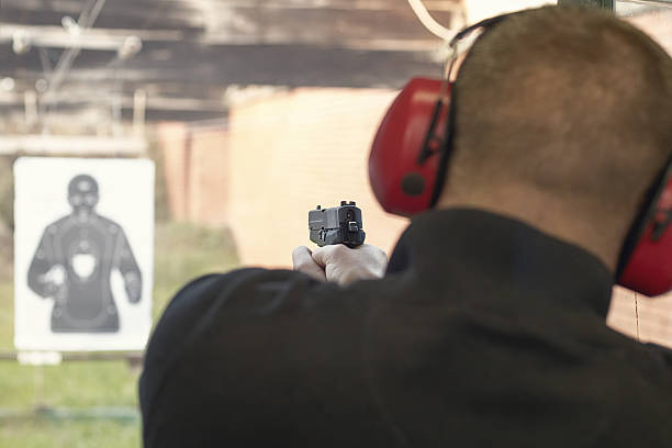 istock Shooting with a pistol. Man aiming pistol in shooting range. 614442044