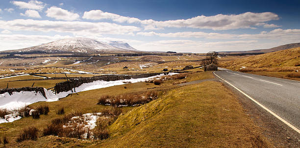 Ingleborough in the snow Snow lies on Ingleborough mountain and Ribblesdale in early spring in England's Yorkshire Dales National Park. ingleborough stock pictures, royalty-free photos & images