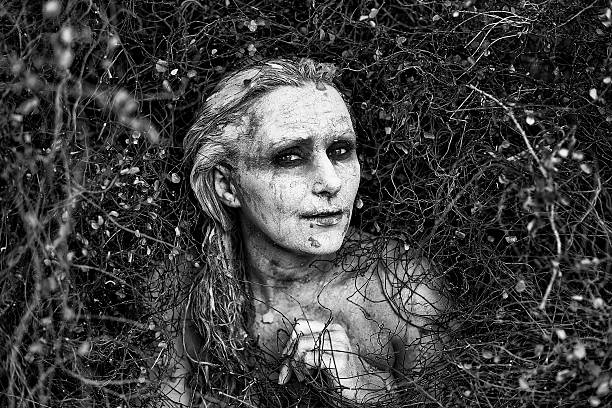 Freaky Woman with face covered in clay staring at the camera