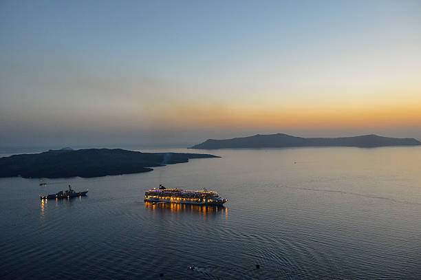 Santorini, Greece - June 21, 2016: Cruise ship in the deep ocean caldera while sun sets.