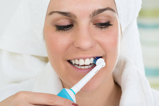 istock Woman Brushing Teeth With Electric Toothbrush 614444518
