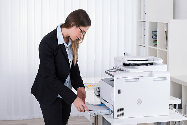istock Businesswoman Putting Papers In Copy Machine 614444698