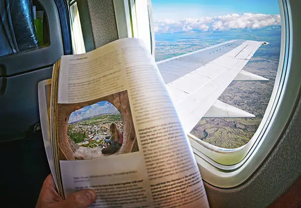 Woman is sitting   by window on a plane with magazine in hands. Concept art.