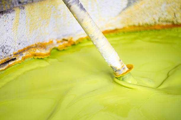 A paint mixing machine stirring lime green paint (close-up) in an old vat.