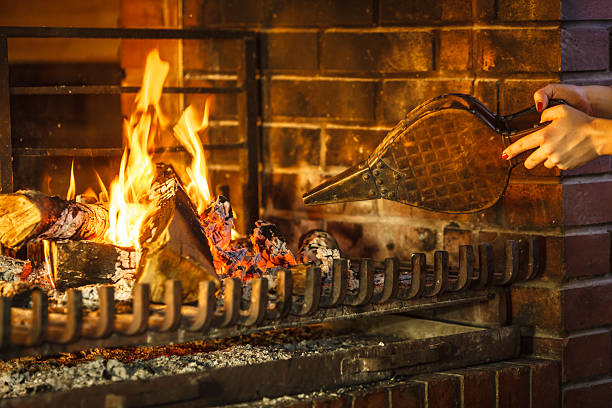 Closeup hands fireplace making fire with bellows. Closeup of human hands at fireplace making fire with bellows. Person heating warming up and relaxing. Winter at home. bellows stock pictures, royalty-free photos & images