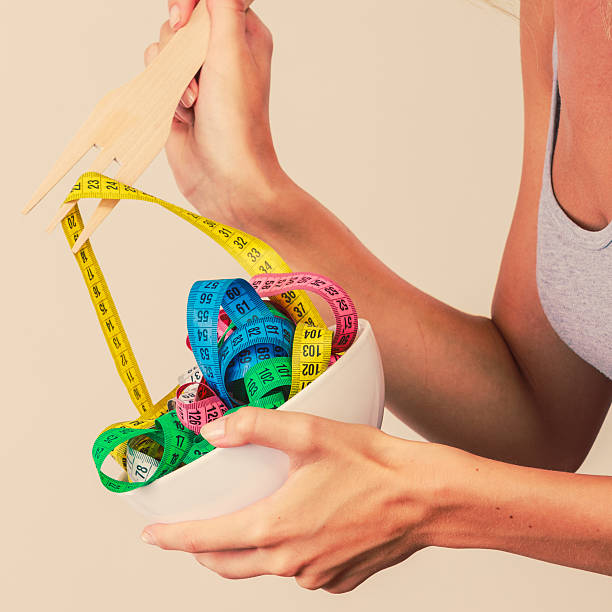 istock Diet. human hand and measuring tapes in bowl 614447308