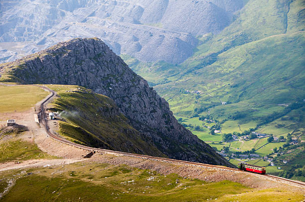 Snowdon Mountain Railway train A train descends from the summit of Snowdon Mountain on the narrow gauge rack mountain railway with the Llanberis valley and spoil heaps of Dinorwig slate quarry in the distance. snowdonia stock pictures, royalty-free photos & images