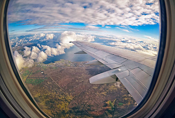 вид из окна самолета на зелены�е поля, облака и море - mountain range earth sky airplane стоковые фото и изображения