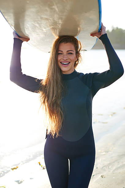istock Strong beautiful young woman with surf on the beach 614492492