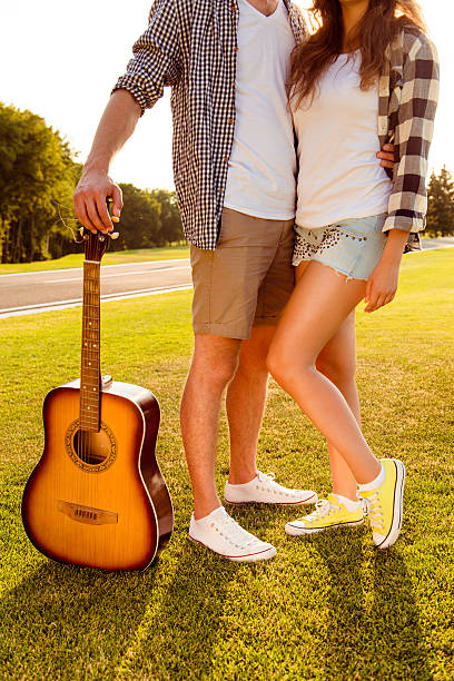 istock Man's and woman's legs with guitar on the lawn 614492708