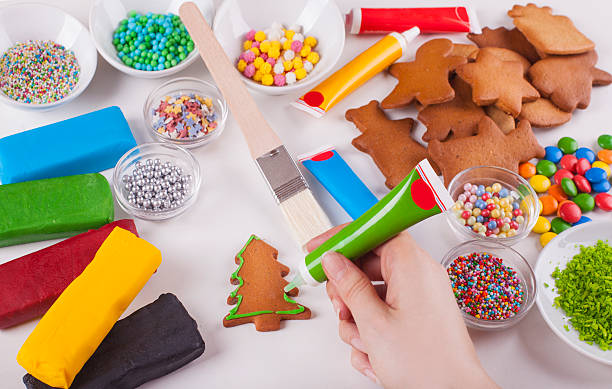 istock Decorating Christmas tree shaped gingerbread cookies with green icing 614492932