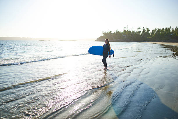 istock Strong beautiful young woman with surf on the beach 614496530