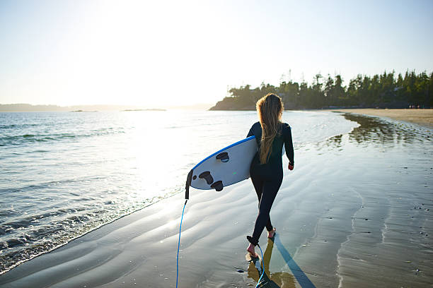 istock Strong beautiful young woman with surf on the beach 614497290