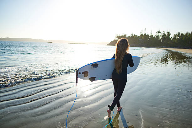 istock Strong beautiful young woman with surf on the beach 614497460