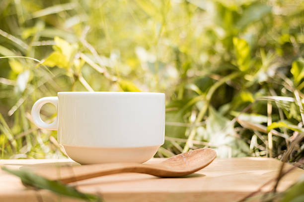 istock White cup of coffee on natural green background 614499074